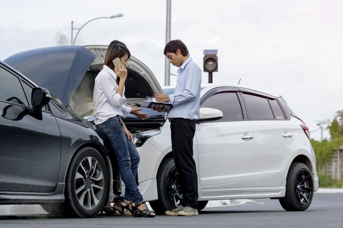 Woman driver calls for instruction during insurance agent review the dammage of the car after accident