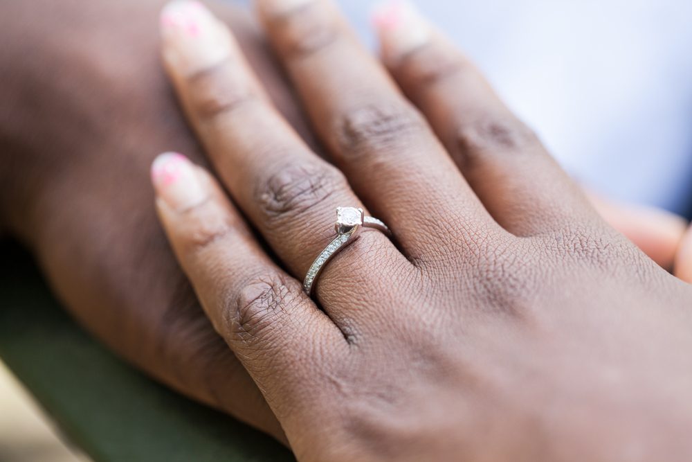 Hands of an nigerian couple. She is wearing an engagement ring.