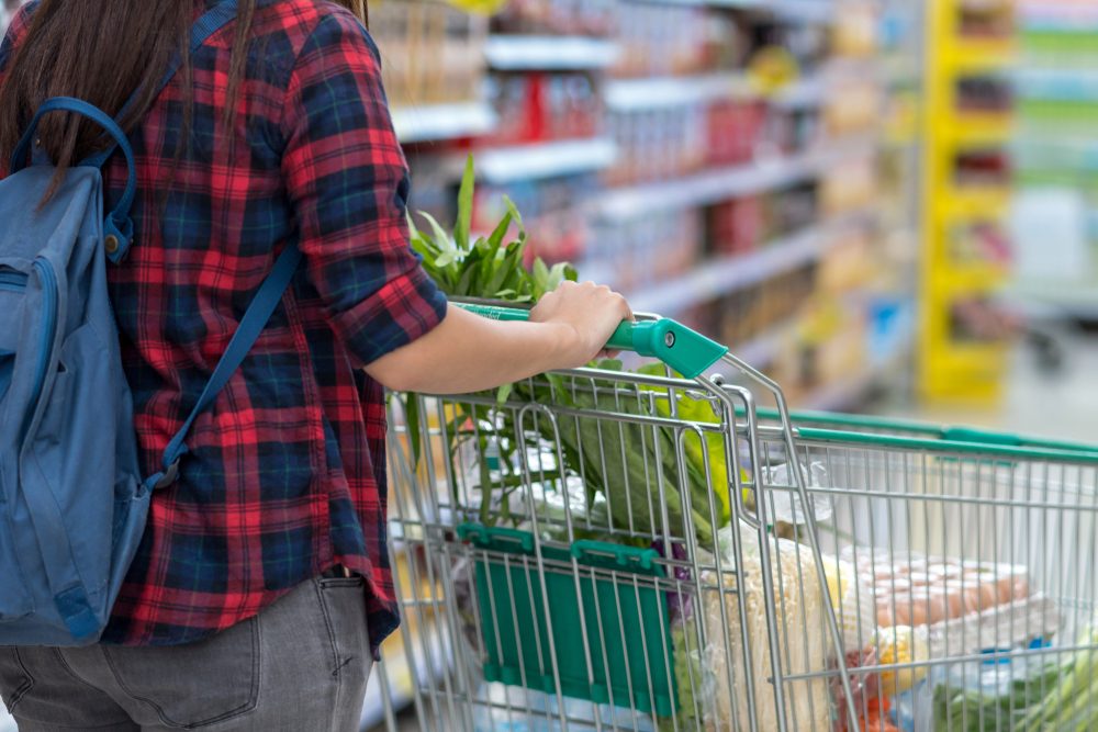 Closeup Young Asian women Hand holding the trolley for shopping over the store blurred in department store bokeh background