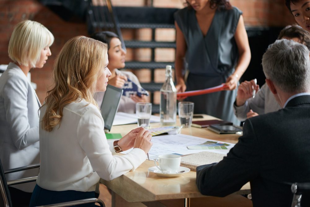 Business people meeting around a boardroom table discussing creative concept