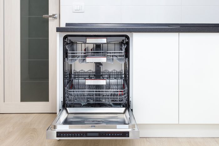 Build-in dishwasher with opened door in a white kitchen