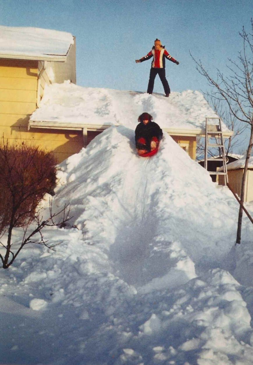 The Blizzard of 1979 dumped a lot of snow on my house. Between 7 and 10 inches of snow were already on the ground, after an earlier blizzard the previous New Year’s Eve. More snow began to fall with a vengeance on the night of Jan. 12, and it kept piling up until 2 a.m. on Sunday, Jan. 14. I was afraid that my roof would collapse, so when I shoveled the garage roof snow to the ground, the snow pile was as high as the gutter, so made a slide that took the kids down and all the way to the back of the lot. The picture below, shows my 12 year old daughter Debbie pushing her 9 year old brother Dan down the slide.