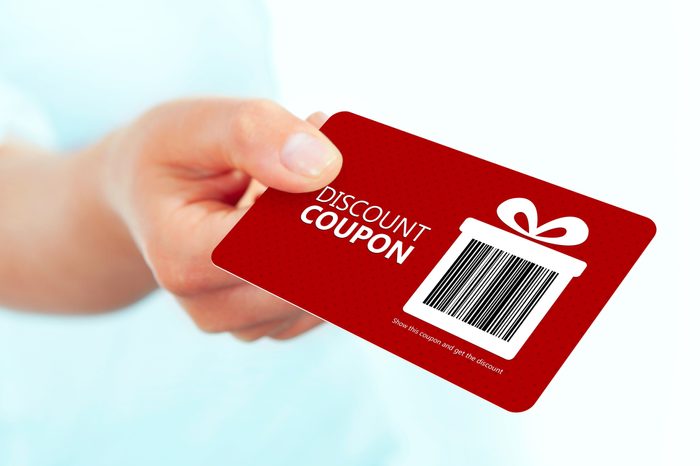 gold christmas coupon holded by hand over white background. focus on coupon.