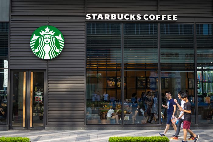 Huizhou, China - Aug. 2017: Some younger men walking outside the Starbucks Coffee store storefront in Huizhou urban