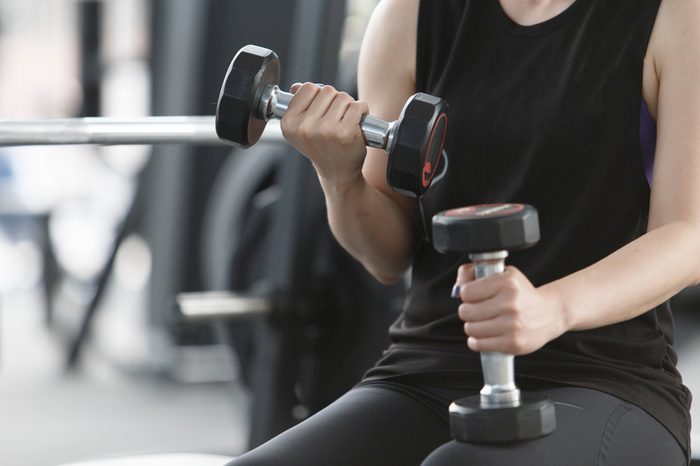 Woman exercising in fitness gym for good health. Athletic young woman exercising equipment at gym, workout in fitness center.