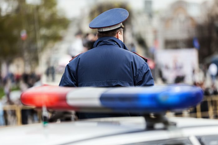 Crime law security service officer cop guarding street near police car with siren light