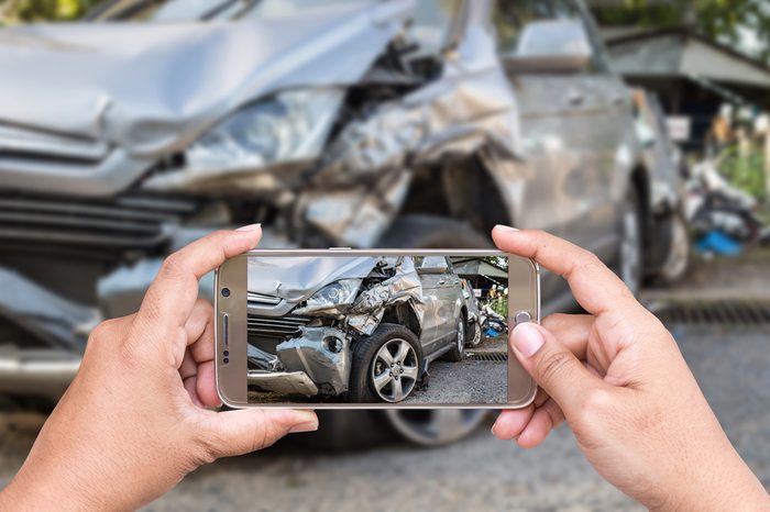 Close up hand of woman holding smartphone and take photo of car accident