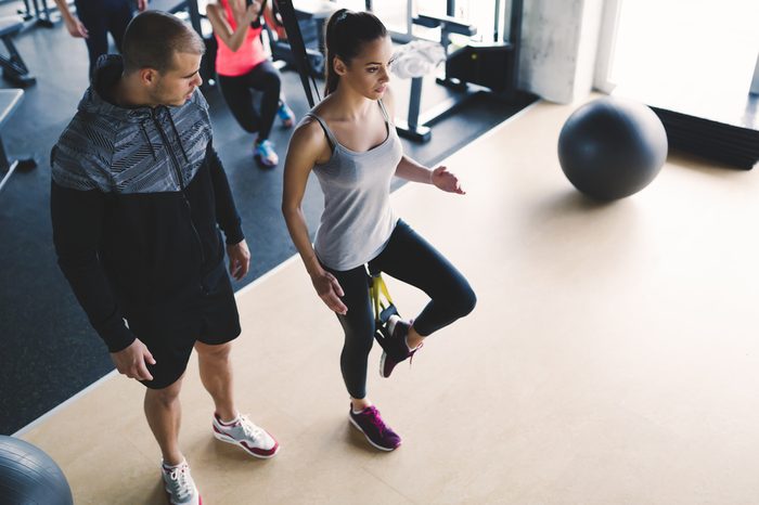 Personal trainer assisting woman lose weight