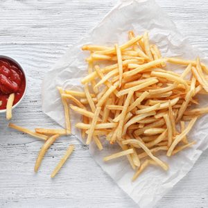 Yummy french fries and sauce in small bowl on wooden background