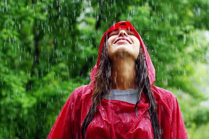 girl smiles, spins and laughs in the rain. the rain falls, the drops fall on his face and the girl is happy with life and nature around. concept of nature and happy life. Adventure, purity.