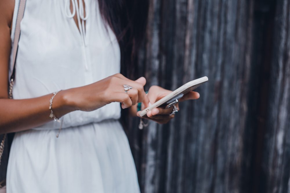 Close up of women's hands holding cell telephone with blank copy space scree for your advertising text message or promotional content, hipster girl watching video on mobile phone during coffee break