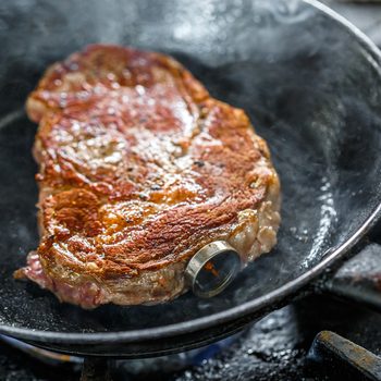 Grilled pork steak with meat thermometer in a frying pan