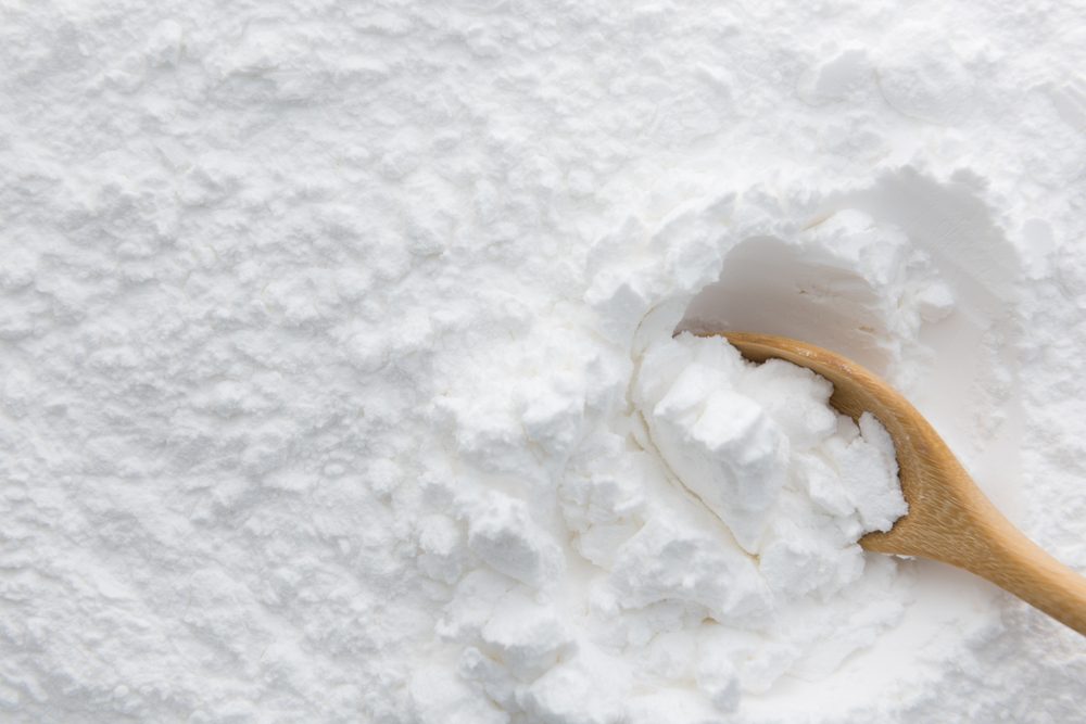 Close-up of tapioca starch or flour powder in wooden spoon with starch background