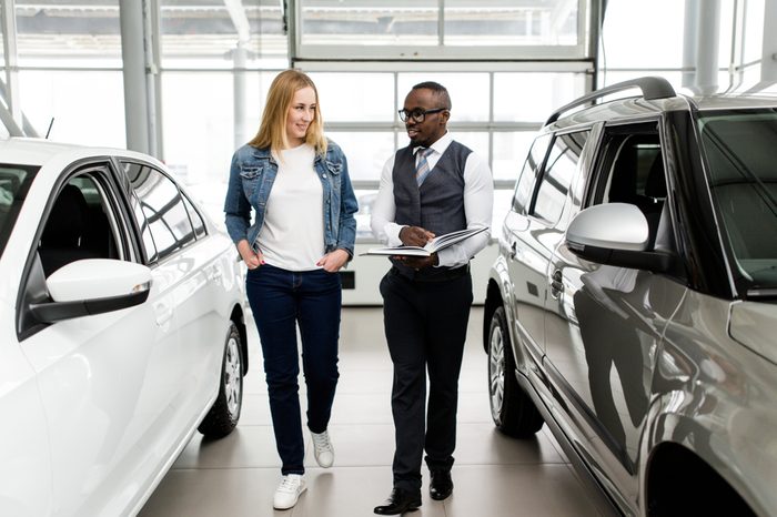 Sales Manager shows the woman new cars in the showroom