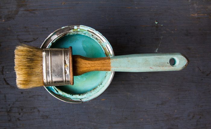 one brush lies on the bank of paint turquoise color on gray wooden background