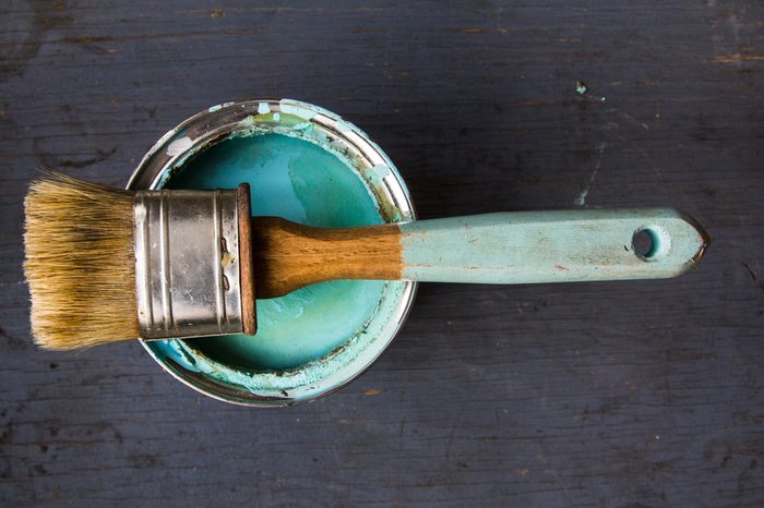 one brush lies on the bank of paint turquoise color on gray wooden background