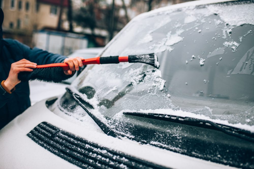 cleaning the glass machine from snow and ice brushing.