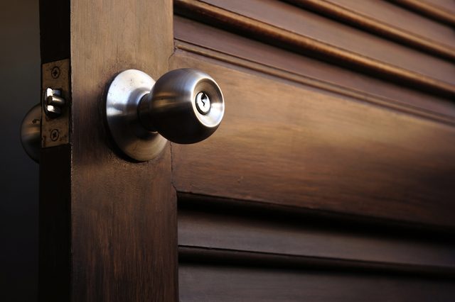 wooden door with grill, stainless door knob or handle on wooden door in beautiful lighting