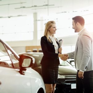 Salesperson selling cars at car dealership