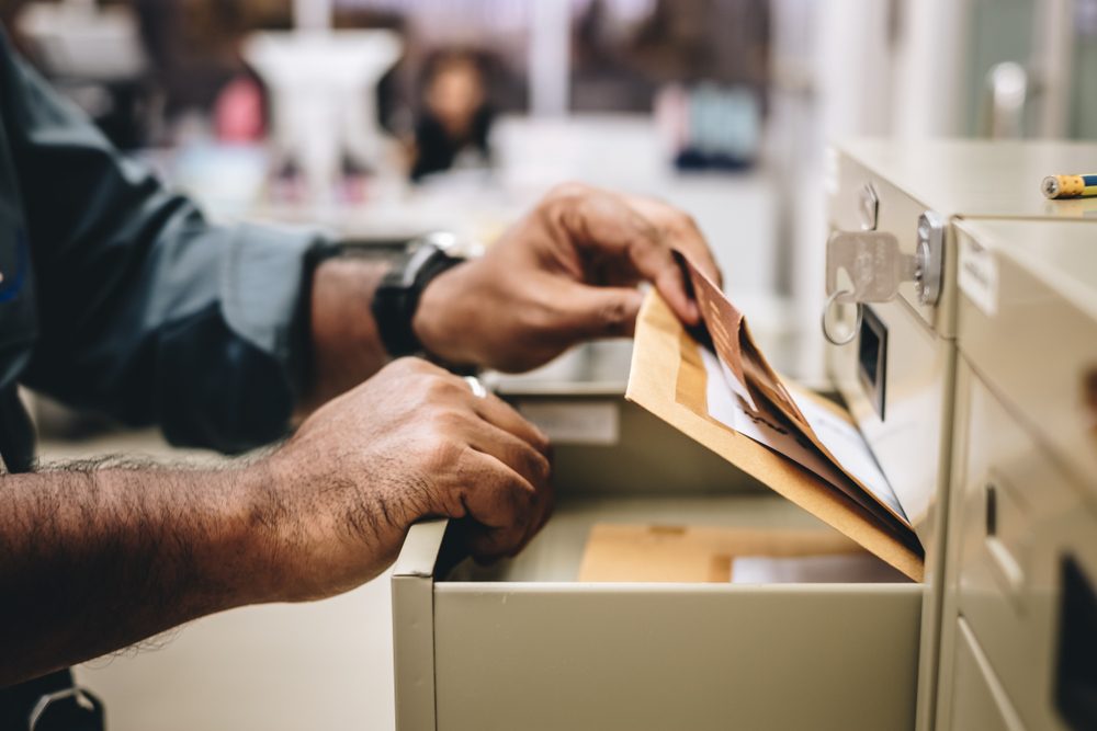 a hand of office employee choose and pick a folder of document paper from opened office's steel drawer