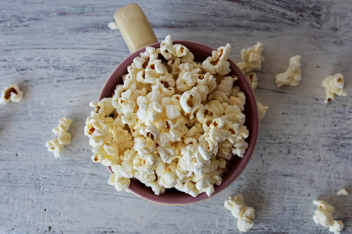 A bowl of delicious caramel popcorn on a white wooden background