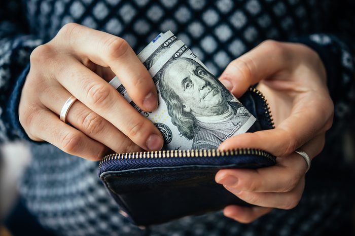 Hands holding us dollar bills and small money pouch