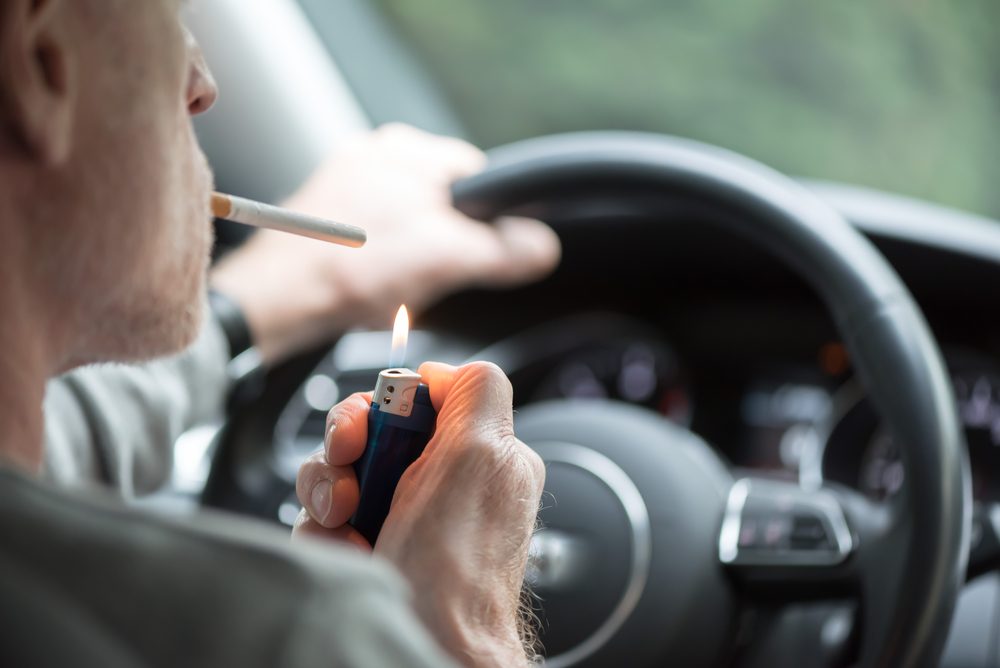 Man driving lighting a cigarette