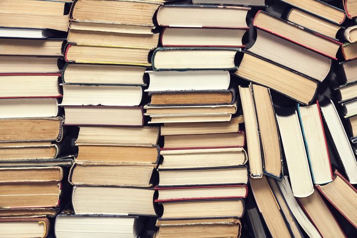 chaotic stack of old books background, selective focus, filter applied