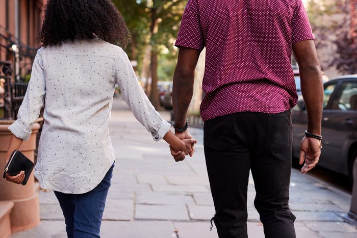 Rear View Of Couple Walking Along Urban Street In New York City