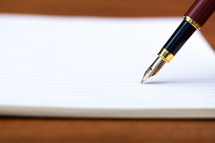 Close up of fountain pen or ink pen with notebook paper on wooden working table with copy space, office desk concept idea. shallow focus.