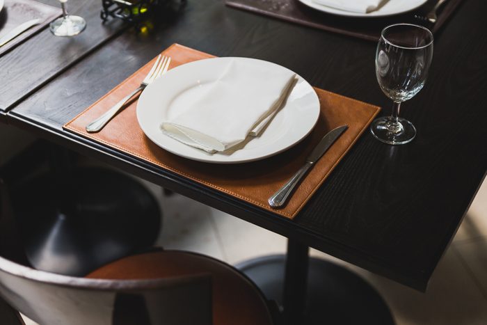 Italian dinner table with cutlery, plate, glass, napkins and naperies with salt and pepper on the table.