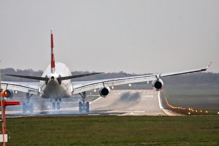 Airplane with four engines landing on runway back view - touchdown with tire smoke
