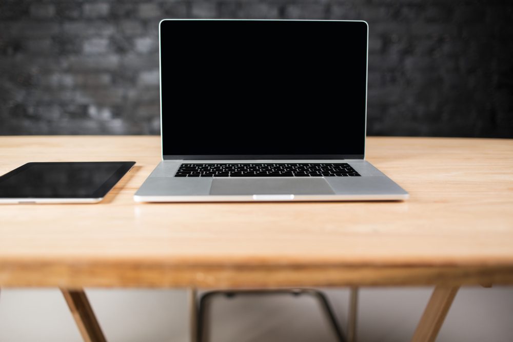Workspace with touch pad and open laptop computer with empty screen space for your advertising text. Modern net-book and digital tablet lying on a wooden table in office interior. 