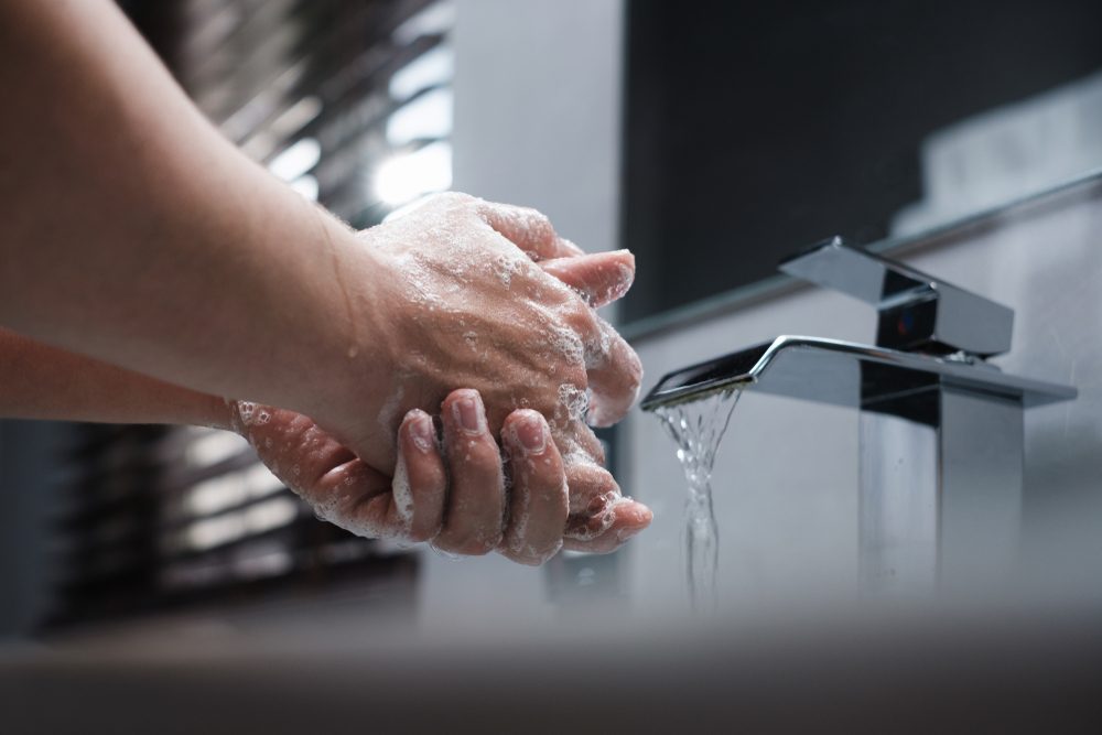 White man lathering and washes his hands with soap in the restroom while keeping the faucet water running. Concept for body hygiene, disease prevention, personal hygiene, and bathroom activity