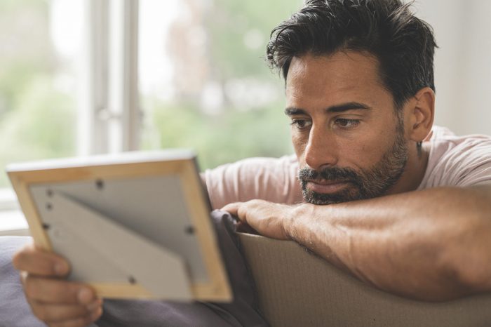 a man gazes longingly at a photo in a frame