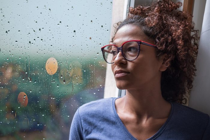 Sad woman looking out of the window on rainy weather