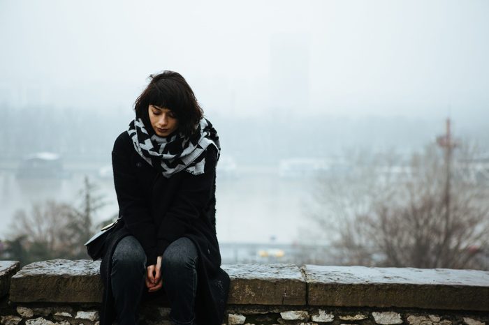 Girl sitting on a wall and having a tough time