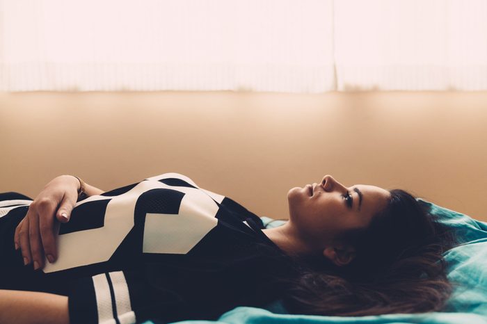 Sad young woman lying in bed