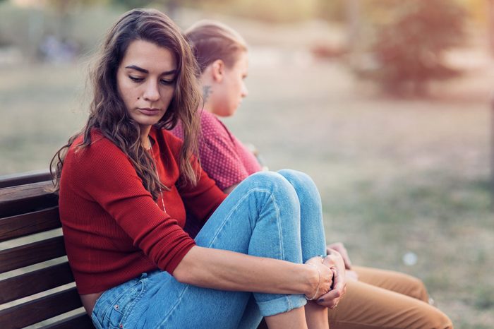 Two young females having some relationship difficulties, sitting at a distance and looking away from each other