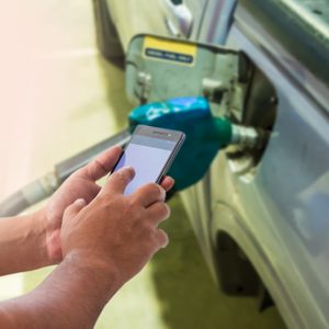 Mobile payment, Cashless society concept. Man using smart phone with blank screen in gas station.