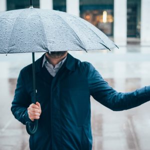 Rainy day in the city and businessman holding umbrella