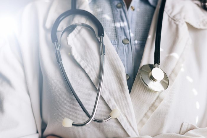 Medical doctor on white background holding a stethoscope. Focus on the stethoscope.
