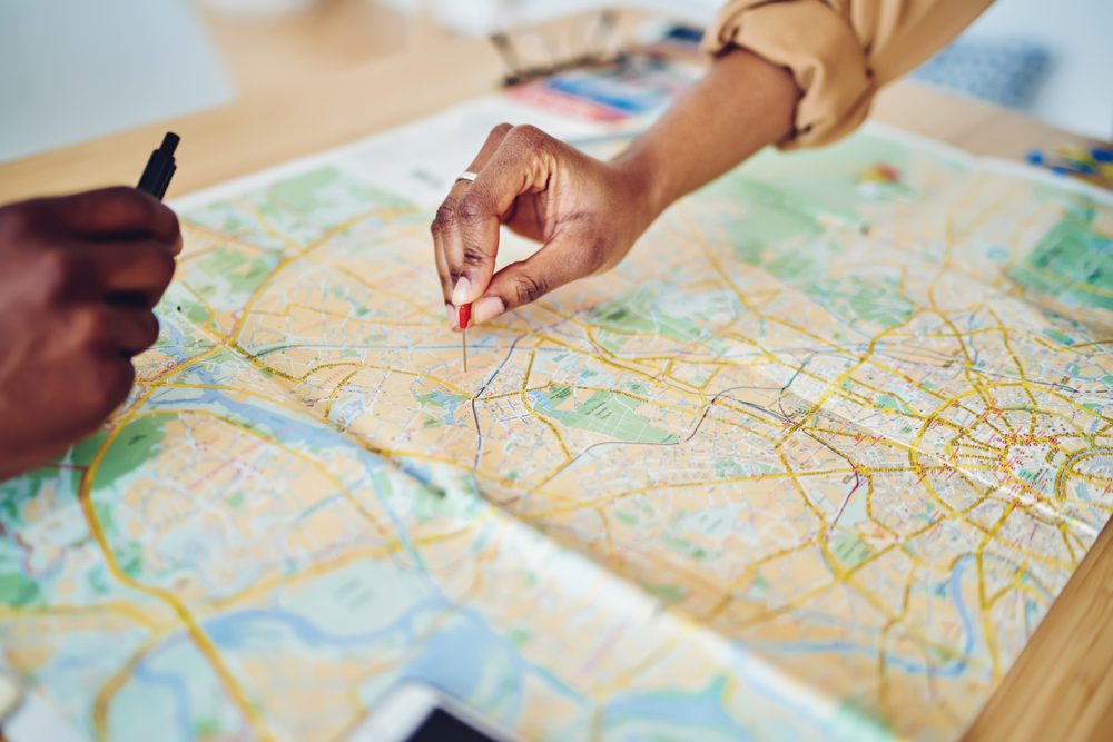 Cropped view of woman's hand pointing on mark on cartography planning touristic route on journey, closeup view of map of country checking direction and location for explore during travel vacation