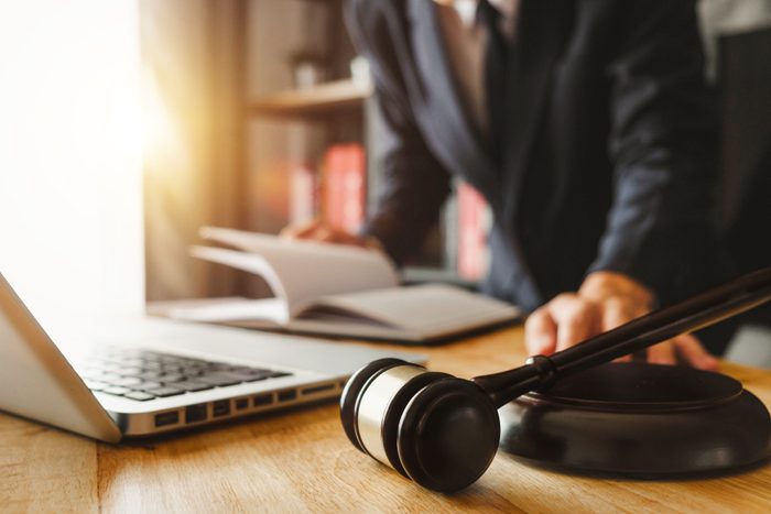 justice and law concept.Male judge in a courtroom the gavel,working with digital tablet computer on wood table in morning light