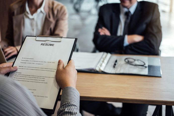 Business man holding his resume and explaining about his profile to two senior manager sitting in during job Interview.
