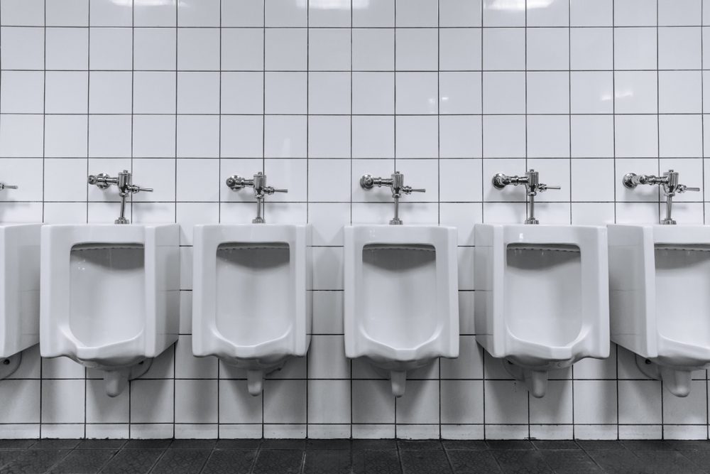 Clean male toilet row of urinals in a public restroom black and white