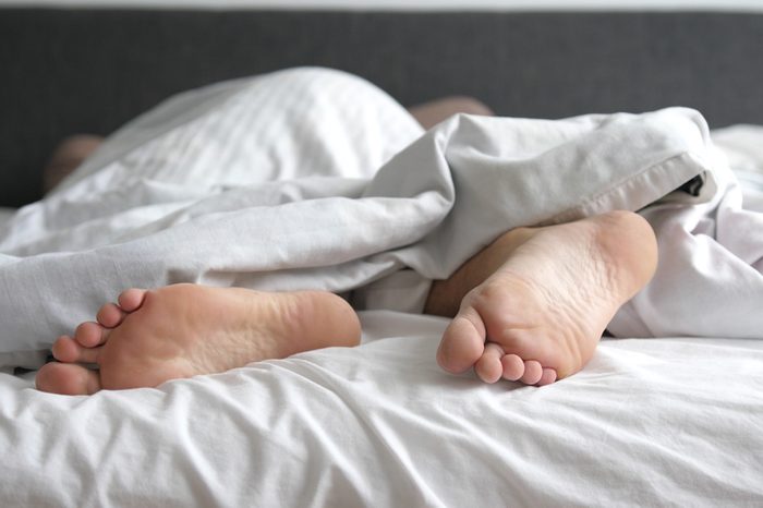 Man sleeping in bed feet relax on holidays. Close up of men feet