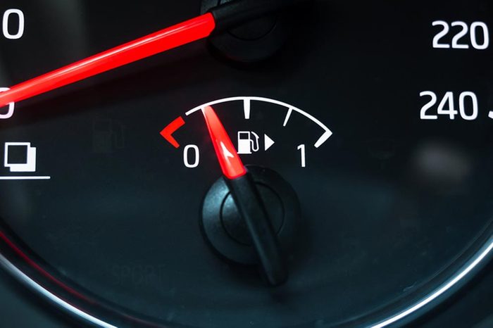 Fuel gauge mounted in round modern car speedometer shows low level of gasoline