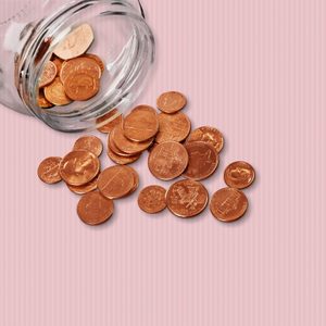 Jar of pennies spilling out on refective white