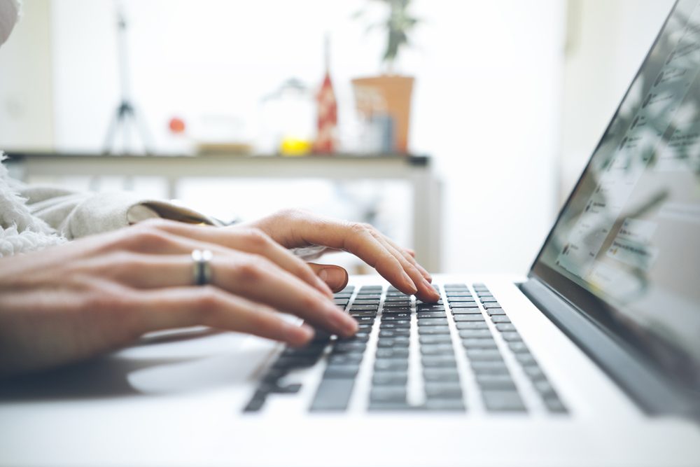 Closeup image of female hands using modern laptop in interior, woman's hands using notebook computer and typing on keyboard while working at home or office